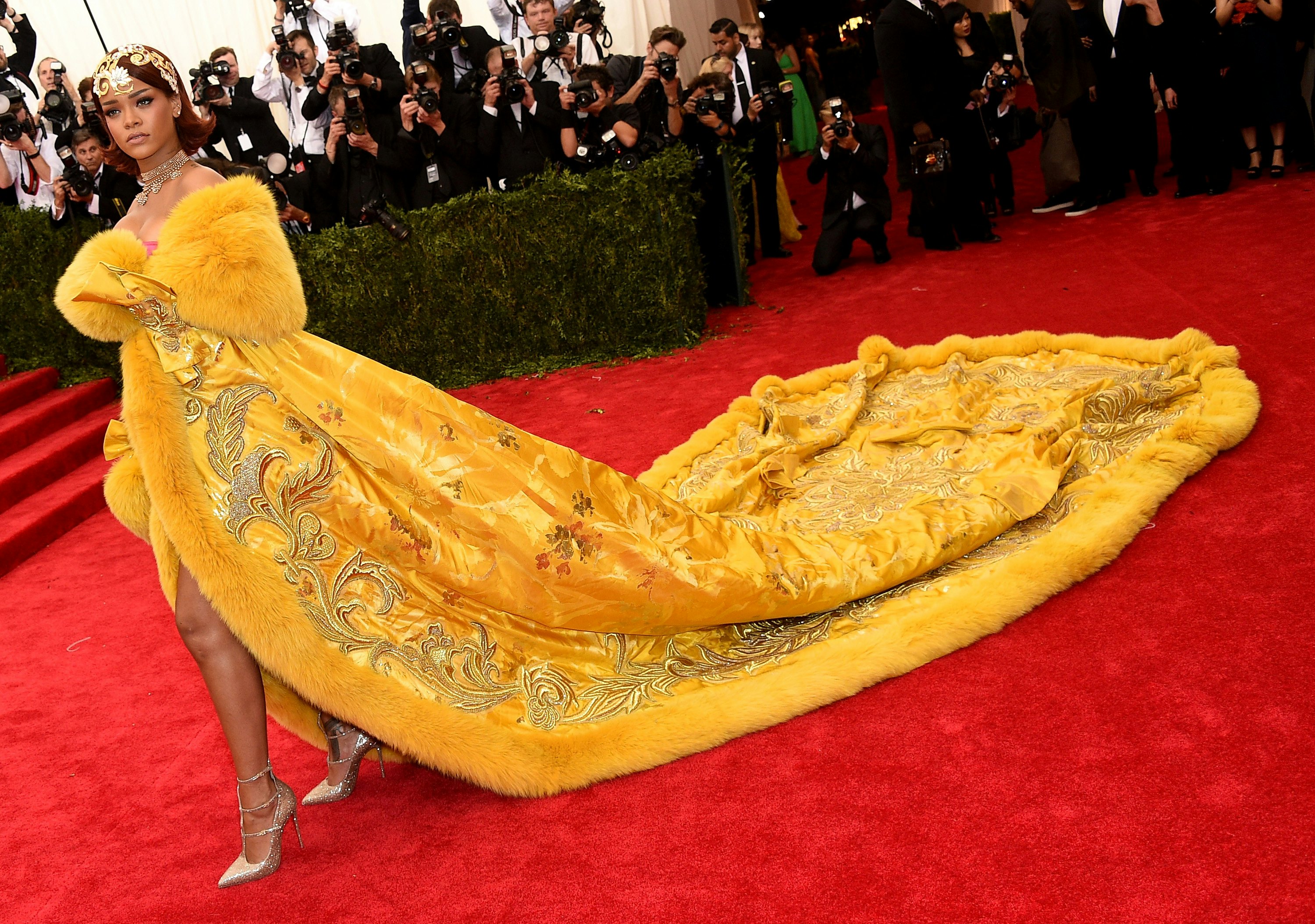 Rihanna at the 2015 Met Gala in a long, majestic imperial yellow robe with ...